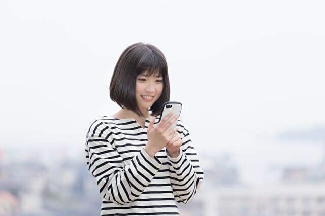 スマホの画面を見て嬉しそうな女性