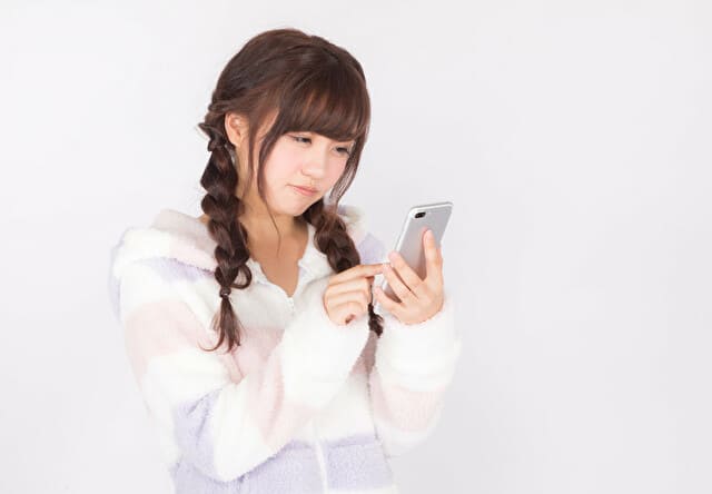 スマホを見ながら悲しそうな顔をする女性