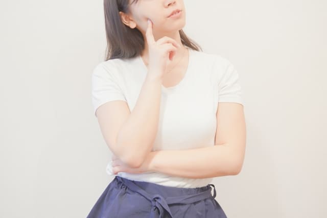 腕を組んで上向きながら「どうだろう」と考えごとをする女性