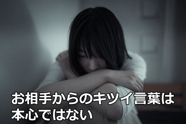 暗い部屋で膝を抱えて悲しんでいる女性と「お相手からのキツイ言葉は本心ではない」の文字