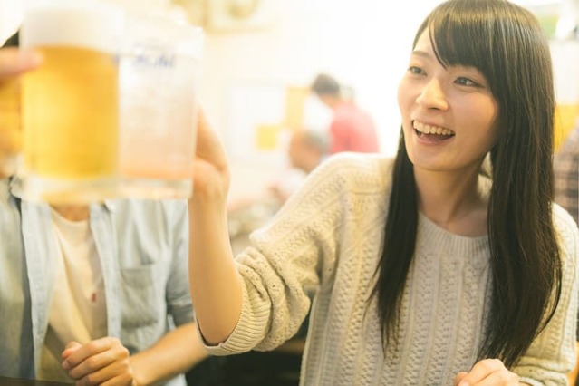 数人で居酒屋で乾杯をする女性